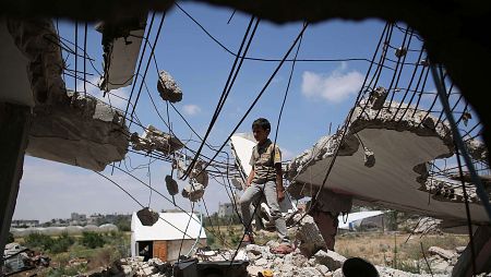 Un niño palestino juega entre los escombros un año después de la guerra de Gaza.