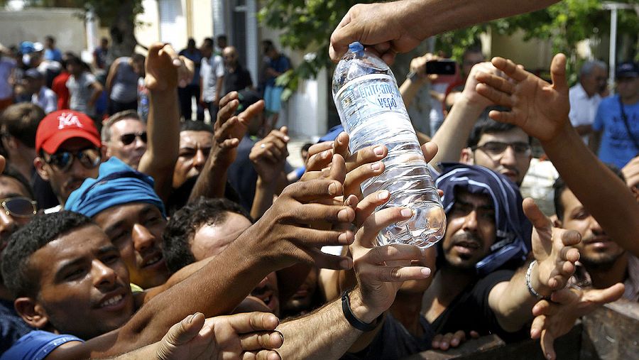 Refugiados sirios y otras personas luchan por conseguir agua en un centro de atención de la isla griega de Kos