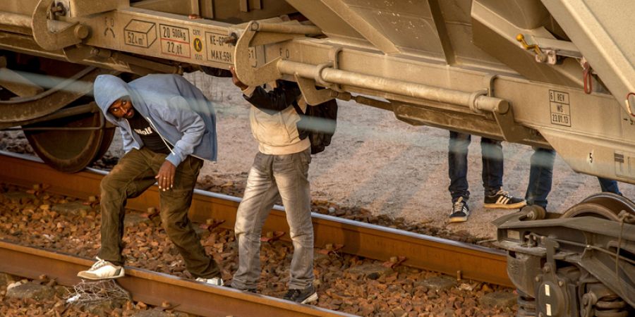 Migrantes se esconden bajo un vagón sobre las vías en Coquelle, cerca de Calais, antes de abordar el Eurotúnel