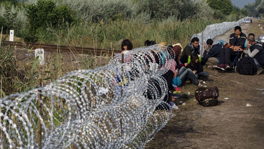 Una familia de migrantes descansa junto a la alambrada en la frontera entre Hungría y Serbia