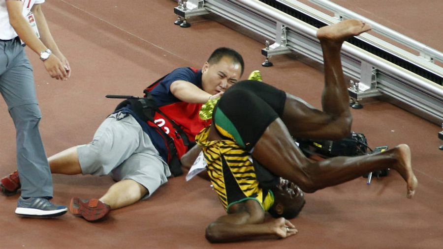 Momento en el que el atleta jamaicano Usain Bolt es arrollado por un operador de cámara y cae a la pista.