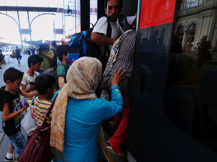 Una familia refugiado se sube a uno de los trenes que han salido este lunes de Budapest rumbo a Austria y Alemania.