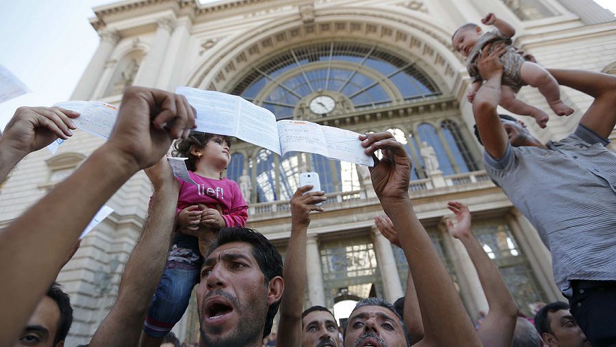 Refugiados muestran sus billetes tras ser desalojados de la estación de trenes de Keleti, en Budapest, cuando pretendían llegar a Alemania