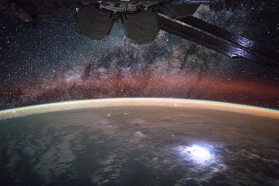 Vista de los paneles solares en la Estación Espacial Internacional iluminados por las luces de la Tierra