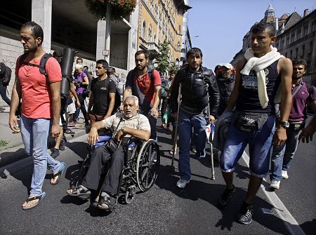 Varios jóvenes ayudan a Imad, de 54 años, a llegar a Alemania en su silla de ruedas.