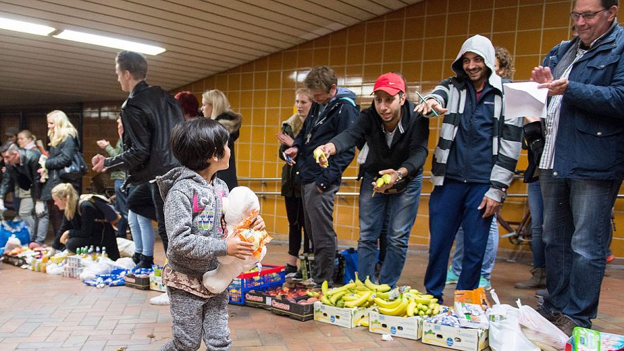 Voluntarios ofrecen alimentos a una niña refugiada recién llegada a Hamburgo