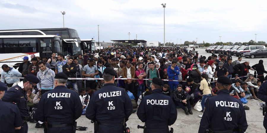 Agentes de policía vigilan a un grupo de refugiados en la frontera entre Hungría y Austria, en Nickelsdorf (Austria)