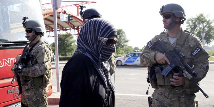 Una migrante camina escoltada por soldados húngaros en la frontera croata hacia un autobús con destino a Beremend en Hungría