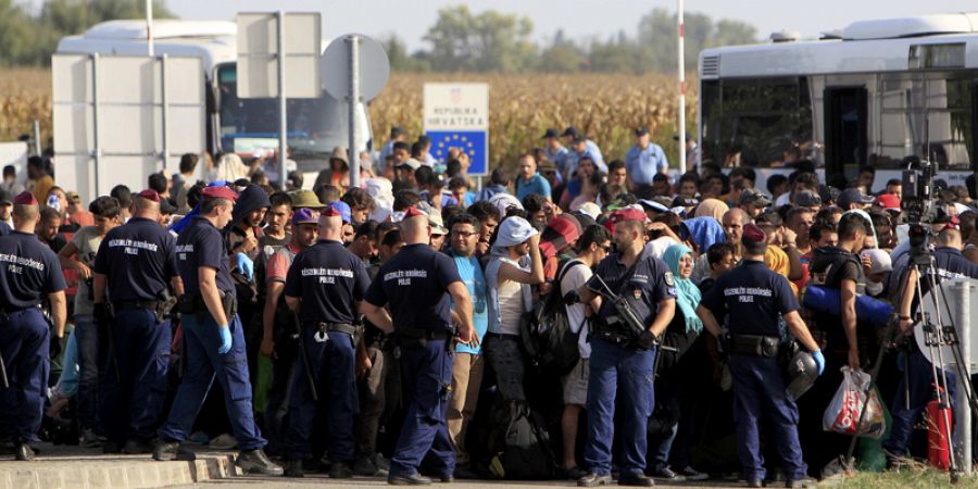Policías húngaros vigilan a los migrantes que serán dirigidos en autobús desde la frontera croata hacia Beremend en Hungría