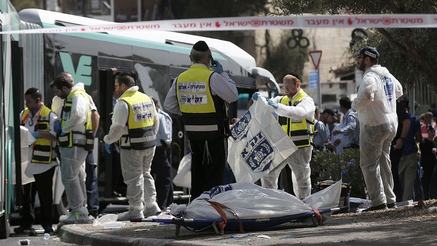 Voluntarios israelíes junto a un cuerpo en el lugar en el que dos palestinos han abordado un autobús y han atacado a sus ocupantes, cerca de la localidad palestina de Yabal Mukaber, en Cisjordania. AFP PHOTO / THOMAS COEX