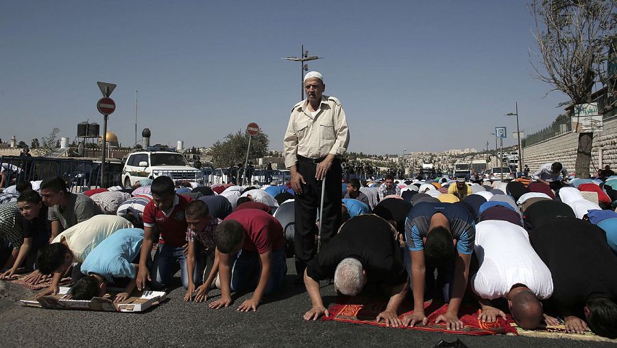 Fuerzas de seguridad de Israel montan guardia mientras musulmanes palestinos rezan en el barrio de Ras Al Amud, en Jerusalén, el 16 de octubre de 2015. Israel ha restringido la entrada en la Explanada de las Mezquitas a los varones de más de 40 años.