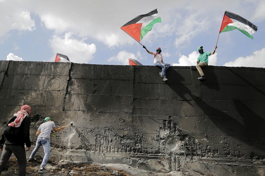 Un grupo de jóvenes palestinos intenta agujerear el muro que separa Cisjordania de Jersualén