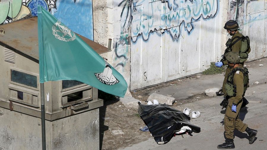 Soldados israelíes junto al cuerpo del palestino abatido en Hebrón, supuestamente tras apuñalar a un guardia de fronteras, el 29 de octubre de 2015. REUTERS/Mussa Qawasma