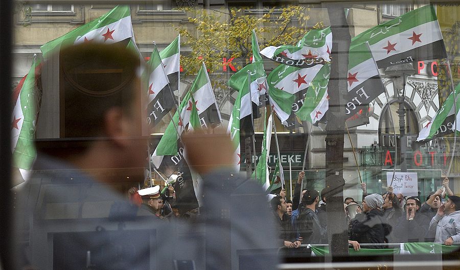 Varias personas ondean banderas sirias durante una protesta ante el Hotel Imperial de Viena, que acoge la cumbre multinacional.