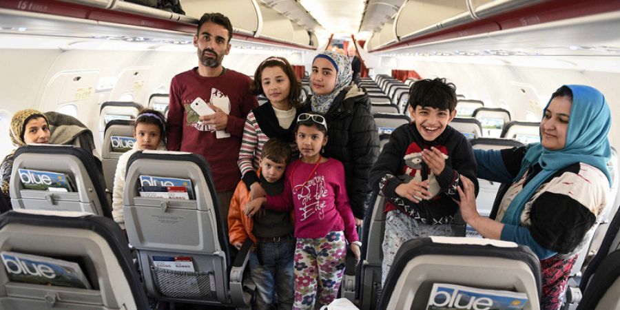 Refugiados iraquíes dentro del avión que les llevará de Atenas a Luxemburgo como parte del primer grupo de 30 migrantes reubicados por la UE