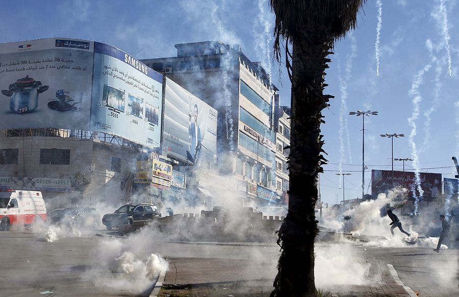 Varios palestinos huyen del gas lacrimógeno lanzado por los israelíes durante los enfrentamientos de Hebrón