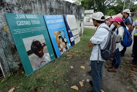 Visitantes observan fotografías de niños desaparecidos hace treinta años durante un alud, en Armero.