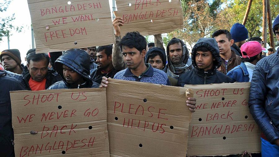 Migrantes de Bangladesh sostienen pancartas pidiendo ayuda en la frontera entre Grecia y Macedonia, en Idomeni, el 24 de noviembre de 2015.  AFP PHOTO / Sakis Mitrolidis