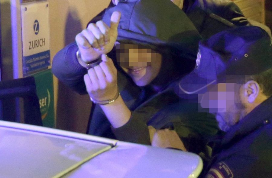 El menor de edad que agredió a Rajoy, saluda mientras es detenido.