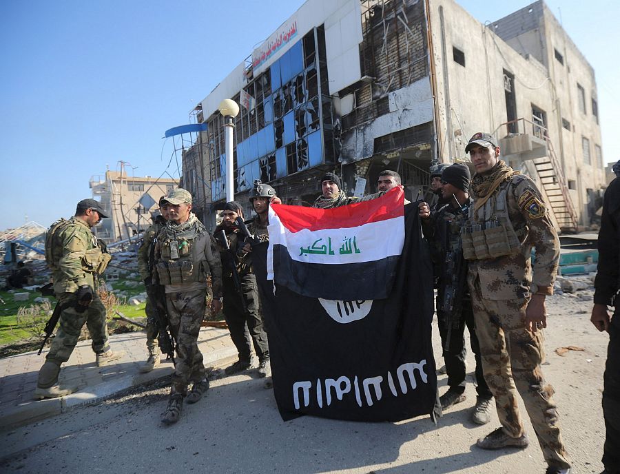 Soldados iraquíes muestran, junto a su bandera, una bandera del Estado Islámico arriada del complejo gubernamental de Ramadi.