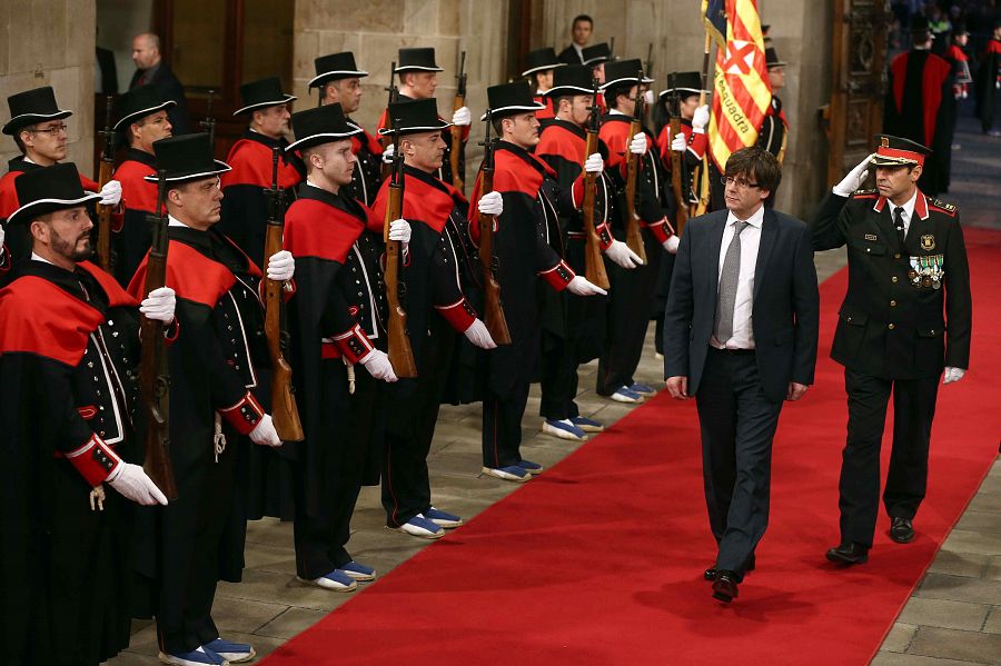 Puigdemont pasa revista a los Mossos d'Esquadra a su llegada al Palau de la Generalitat para tomar posesión de su cargo.