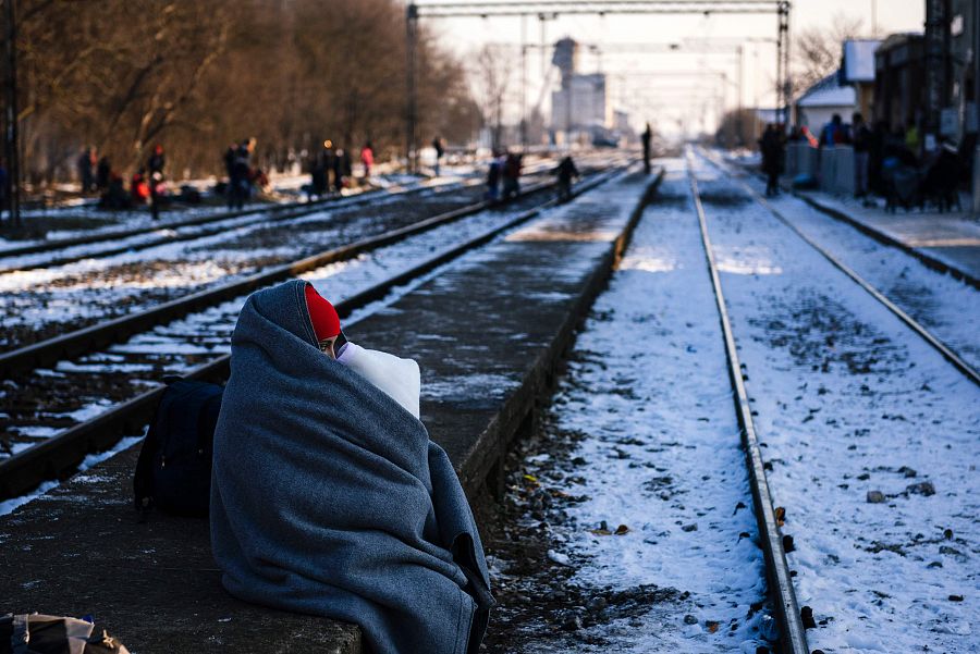 Una mujer abraza a su hijo mientras espera un tren bajo un frío invernal en las vías de Presevo, en Serbia.