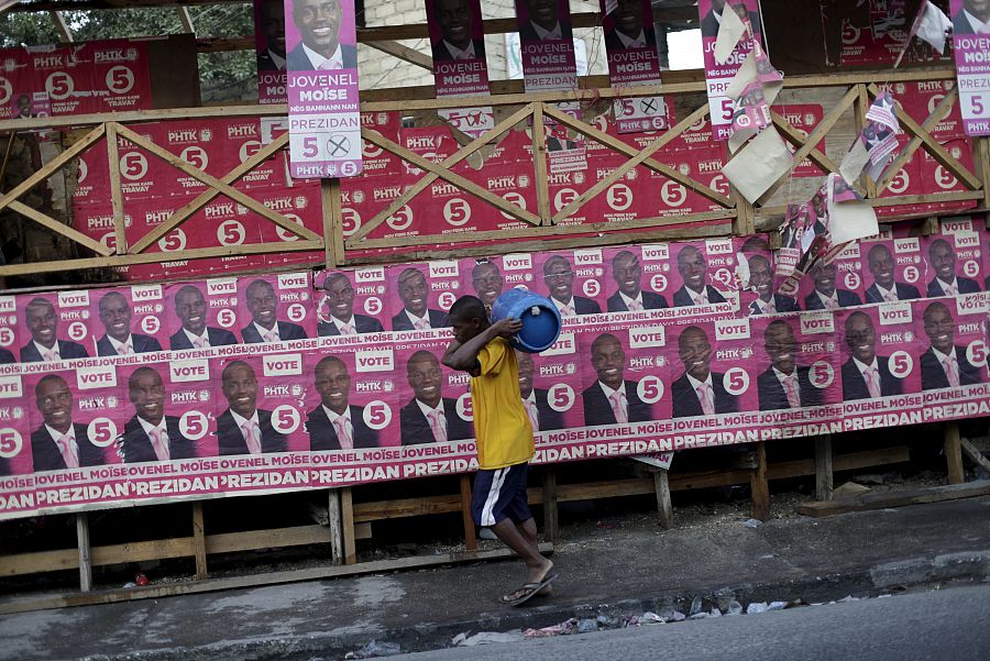 Un hombre pasa en Puerto Príncipe ante una pared forrada de carteles del candidato oficialista, Jovenel Moise