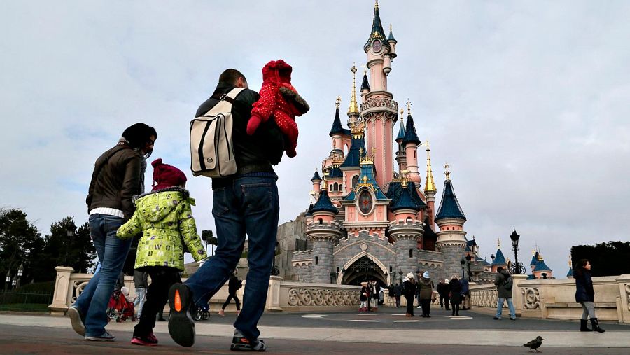 Varios visitantes del parque temático Disneyland París, junto al castillo de la Bella Durmiente