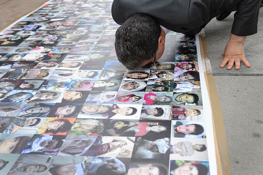 El portavoz de la delegación de la oposición siria, Salem Muslit, besa un mosaico de fotos de niños sirios muertos y desparecidos