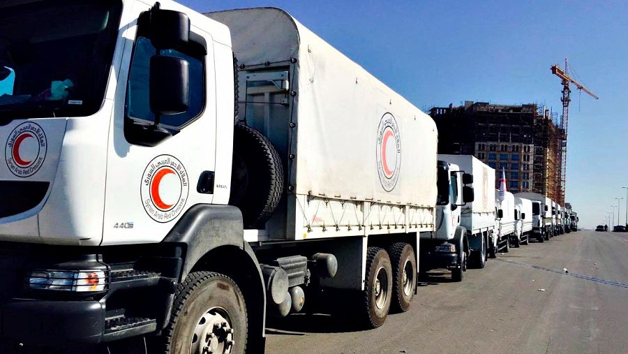 Varios camiones de la Media Luna Roja con ayuda humanitaria esperan en Damasco, antes de partir hacia zonas sitiadas por el régimen