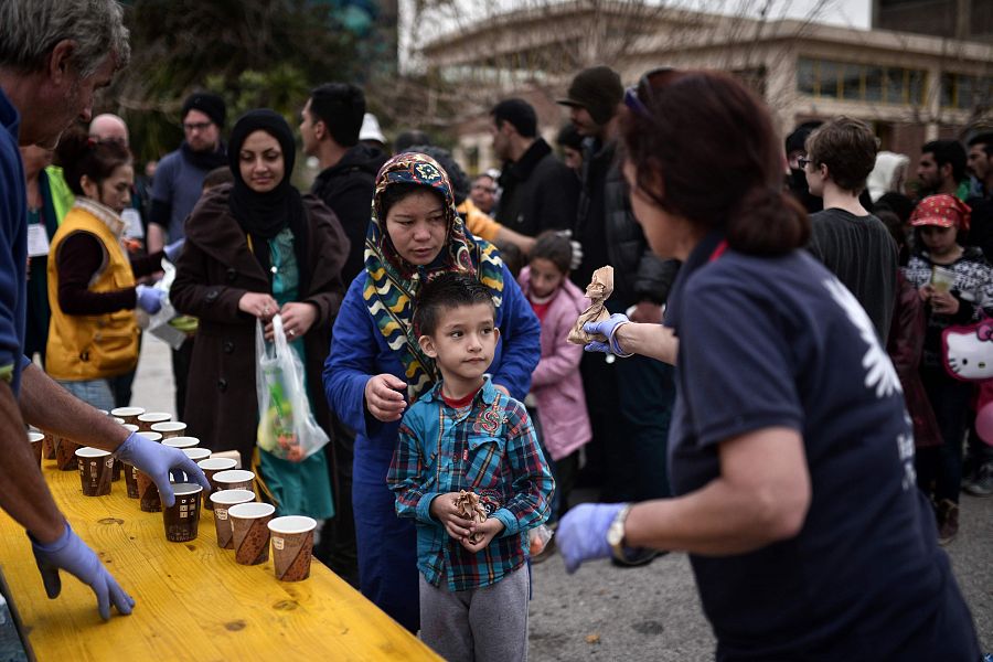 Un grupo de refugiados hace cola en el puerto del Pireo, en Atenas, para recibir comida distribuida por organizaciones humanitarias