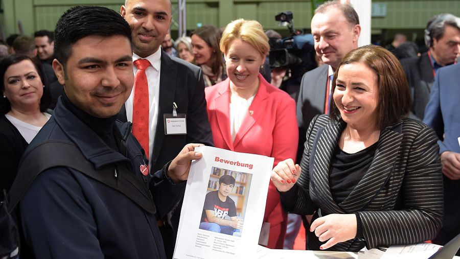 Un migrante afgano muestra su solicitud de empleo ante la responsable en Berlín de empleo