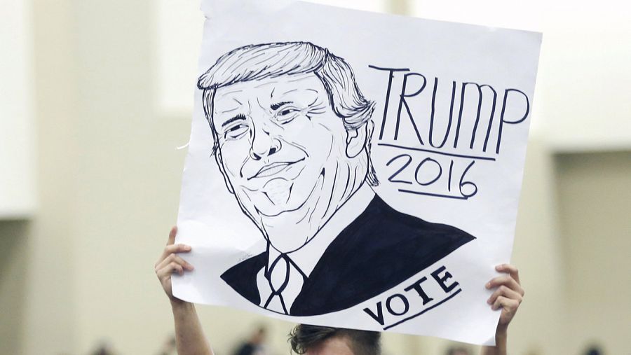 Un partidario de Donald Trump sujeta un cartel con una caricatura del candidato