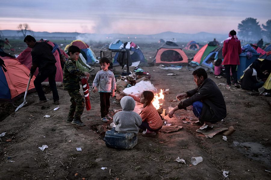 Una familia intenta calentarse en torno a un fuego en el campamento de Idomeni, en la frontera entre Grecia y Macedonia