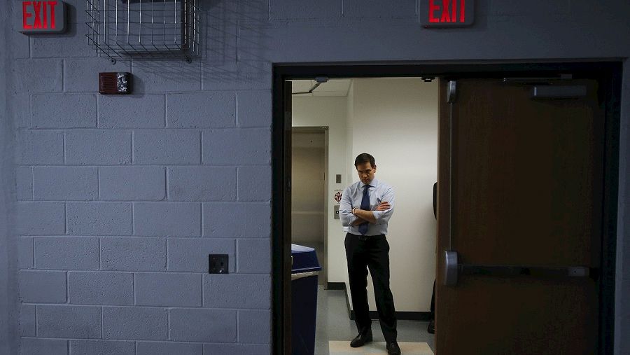 El senador y candidato en las primarias republicanas Marco Rubio escucha en la trastienda de su mitin en Palm Beach, Florida. Sobre la puerta un cartel indica la salida. REUTERS/Carlo Allegri