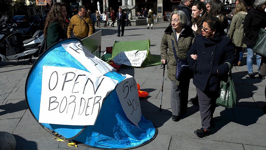Varias personas pasan entre las tiendas de campaña como las que utilizan los refugiados que dieciséis ONG españolas han instalado el 16 de marzo frente a la sede del Ministerio de Exteriores, en Madrid. EFE/Fernando Villar