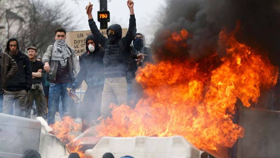 Varios manifestantes en Nantes, junto a unos contenedores incendiados