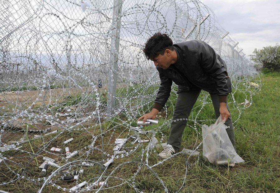 Un migrante recoge los botes vacíos de gas lacrimógenos utilizados por la policía de Macedonia para dispersar a lo refugiados de la frontera.