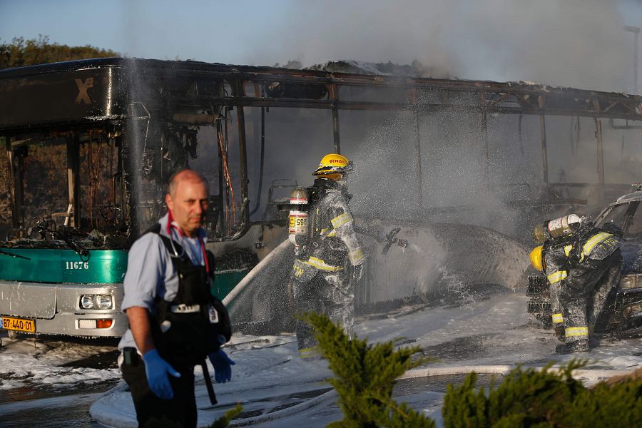 Los bomberos apagan el fuego en uno de los dos vehículos incendiados en el sur de Jerusalén.