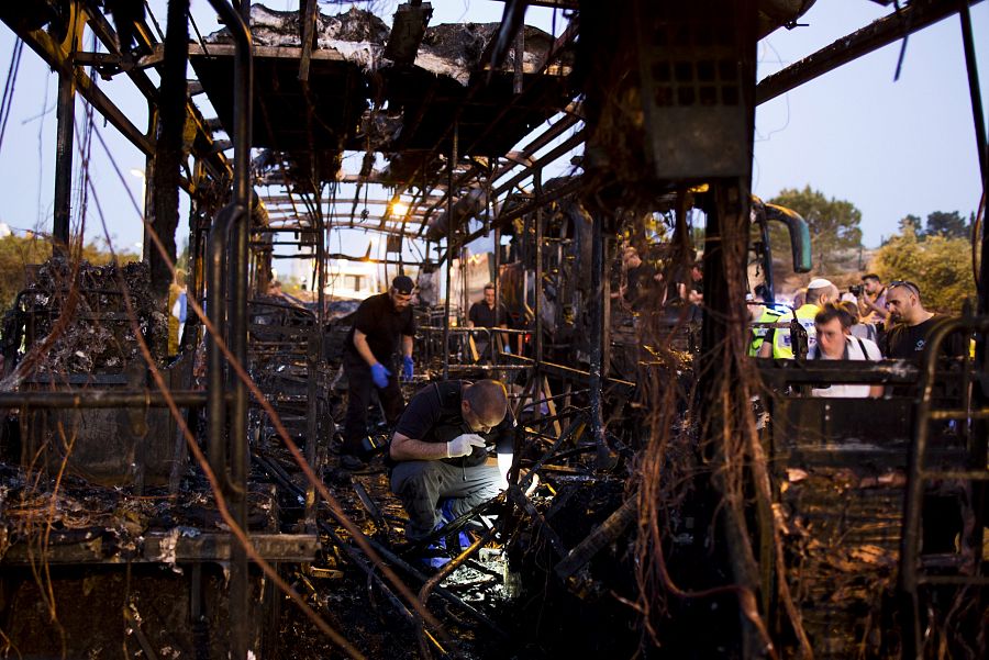 Agentes de seguridad y bomberos inspeccionan los restos del autobús destruido por la explosión registrada en Jerusalén
