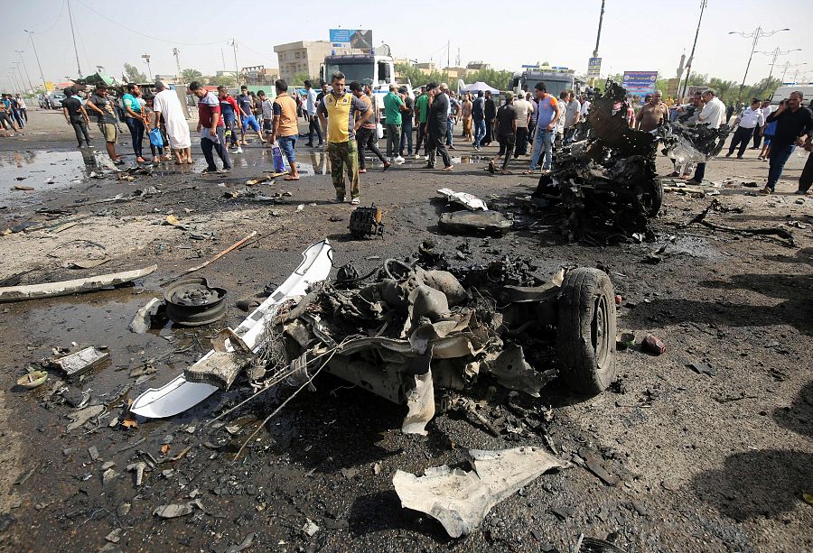 Varias personas comprueban los daños causados por el coche bomba que ha estallado en el barrio de Ciudad Sadr, en Bagdad