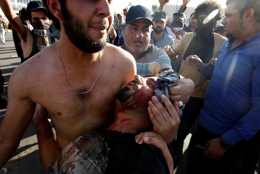 Uno de los manifestantes traslada a un herido en las protestas de Bagdad