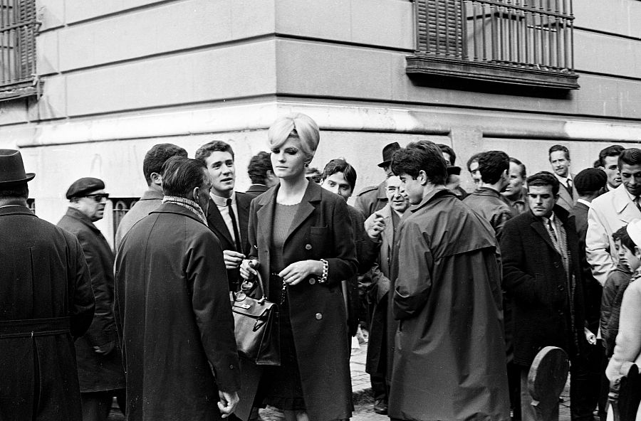 Una modelo pasenado par la calle, bajo la atenta y devoradora mirada de todos los hombres que la observan