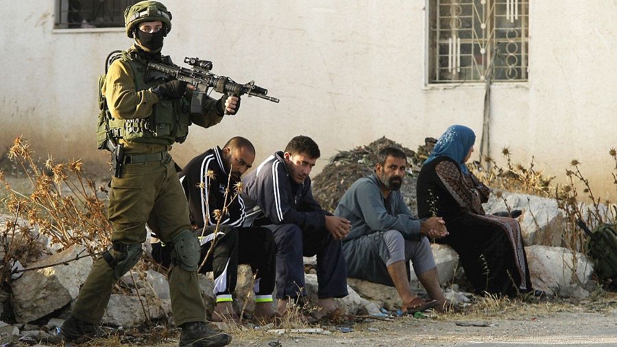 Un soldado israelí vigila a un grupo de palestinos en la aldea de Yatta, cerca de Hebrón, en Cisjordania