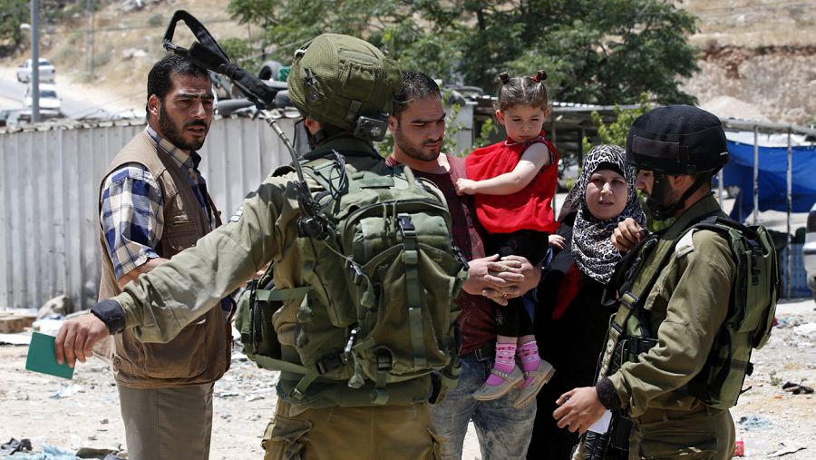 Una familia palestina discute con dos soldados israelíes en un control en Cisjordania