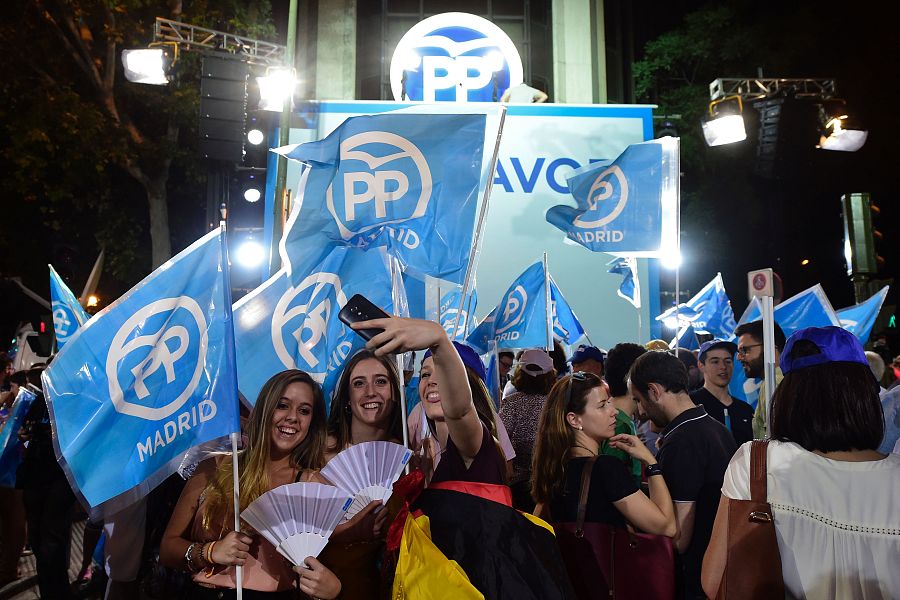 Jóvenes simpatizantes del PP se hacen un selfie junto a la sede del partido.
