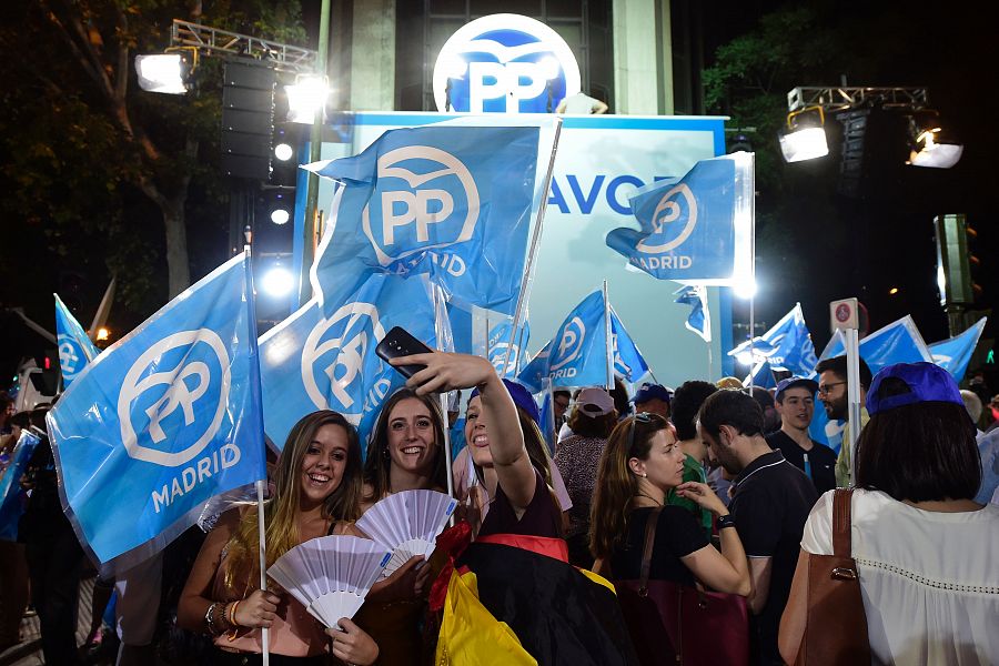 Jóvenes simpatizantes del PP se hacen un selfie junto a la sede del partido.