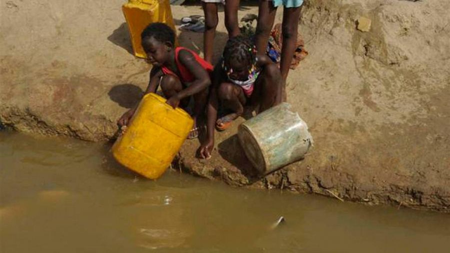 Dos niños intentan recoger agua de un río en Angola