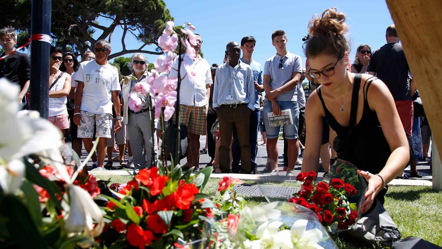 Una mujer coloca un ramo de flores en el lugar donde un camión arrolló anoche a centenares de personas en Niza