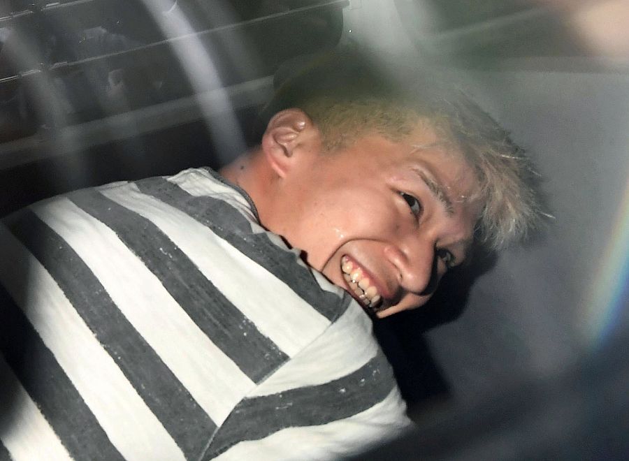 Satoshi Uematsu, el asesino confeso de 19 discapacitados, sonríe al salir de las dependencias policiales en el asiento trasero del coche patrulla.